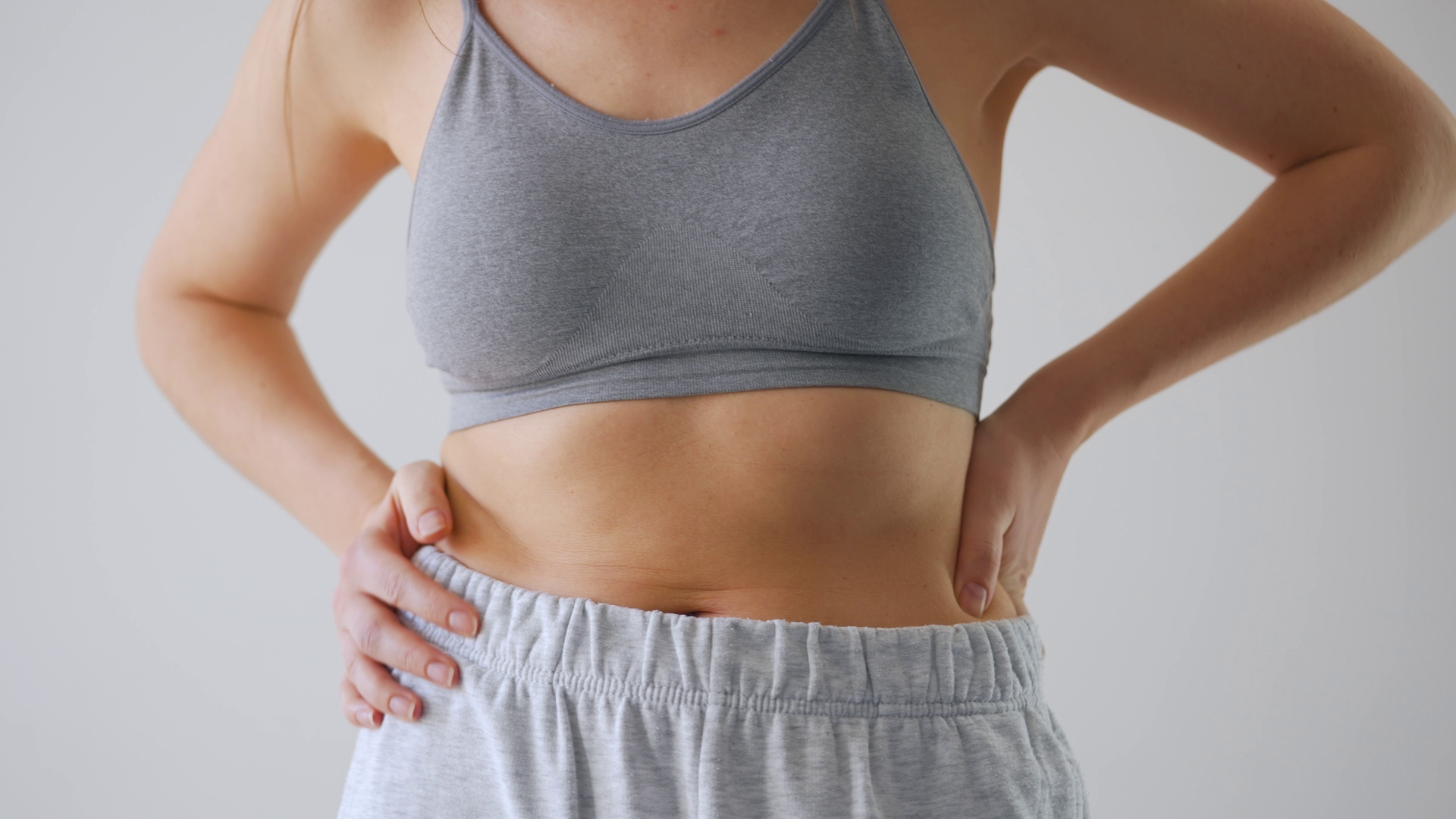Woman touching her abdomen and lower body — lipedema and cellulite affect the same regions but are distinct conditions